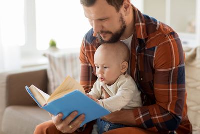 happy father and little baby boy with book at home