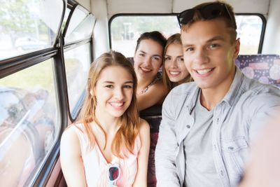 happy teenage friends traveling by bus