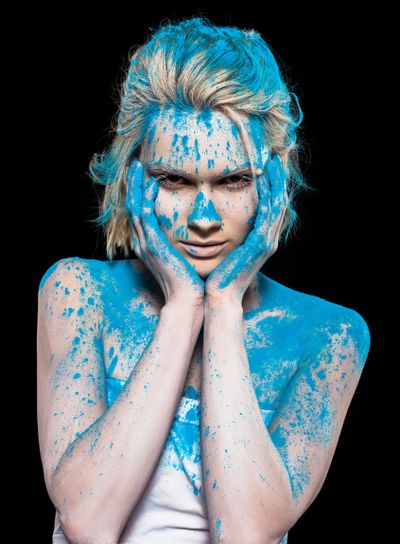 young woman posing in blue powder paint, isolated on black