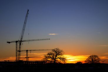 Silhouettes of construction cranes against the evening...