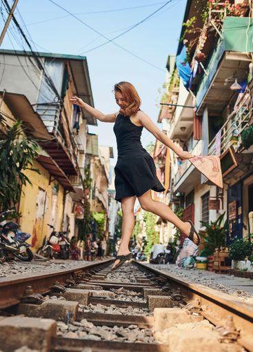 Travel, freedom and jump with woman on train tracks for...