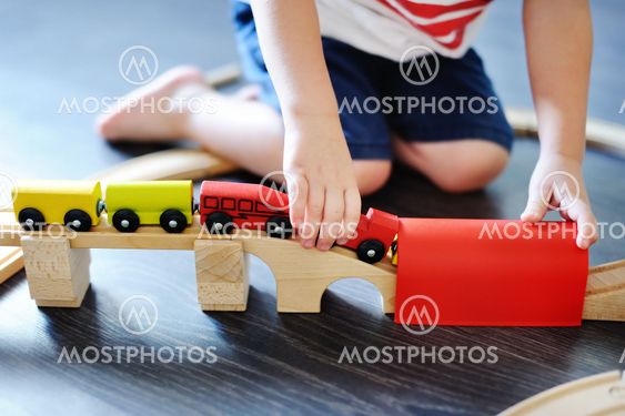 Toddler boy playing with toy wooden train at home