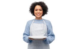 smiling woman in apron holding empty plate