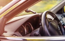 Woman sitting at the steering wheel and typing in...