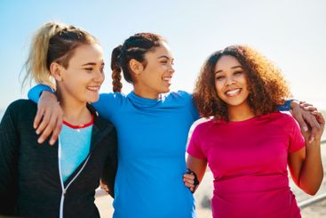 Women, friends and hug for exercise by ocean, smile and...