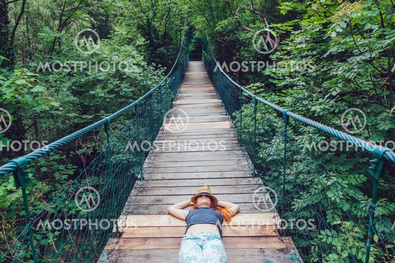 Young woman in the forest lying on the wooden bridge,...