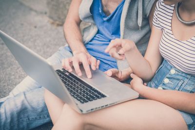 couple of friends young  man and woman using laptop