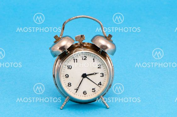 Retro grunge rusty alarm clock blue background