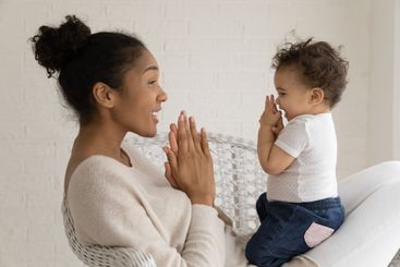 Loving African American mom play with baby daughter