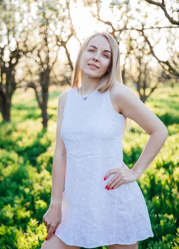 Beautiful blonde woman in summer dress walking in the...