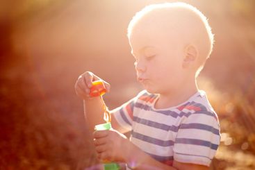 Bubbles, sunset and boy in park with fun, adventure play...