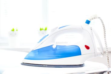 Iron on ironing board on light home interior background