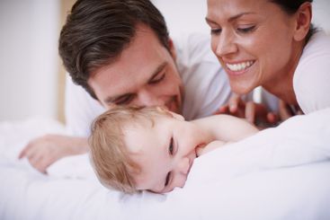 Happy, parents and playing with baby on bed for bonding,...