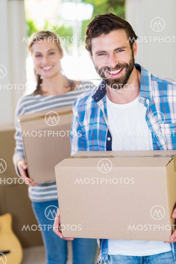 Portrait of young couple holding cardboard boxes