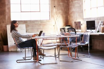 Female Designer Sitting At Meeting Table Working On Laptop