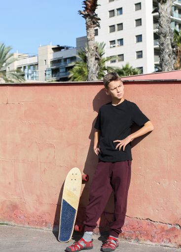 Handsome teenager standing with skateboard. Adolescent...