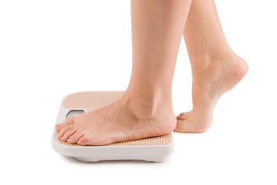 Female feet on scales isolated