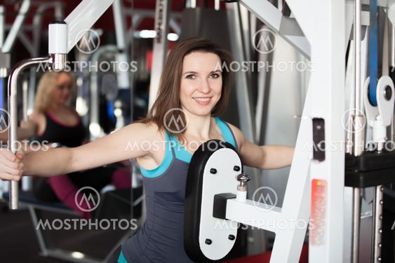 Girl does exercises for arms and shoulders in gym
