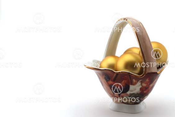 golden egg in porcelain basket on white background