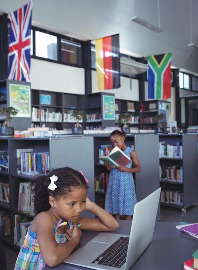 Concentrated girl looking at laptop in library