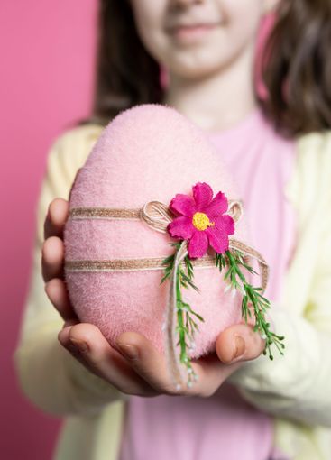 Little joyful kid with fluffy ears shows a pink colored...