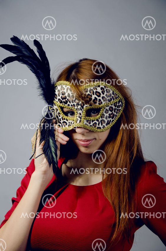 Beautiful young girl in a red dress and mask