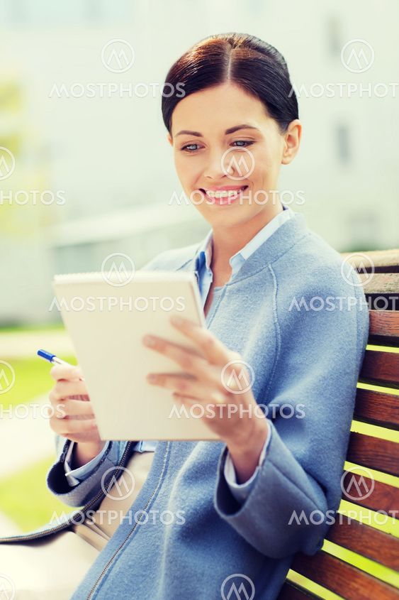 businesswoman reading notes in notepad outdoors