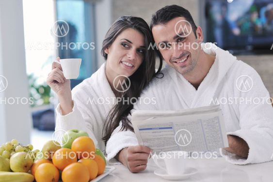 Happy couple reading the newspaper in the kitchen at breakfast