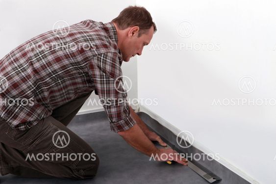 Tradesman laying down linoleum flooring