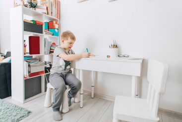 boy concentrating on school work at home, using...