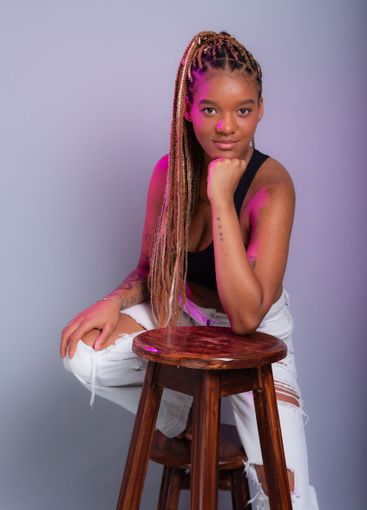 Brunette model with braids in her hair, wearing white...