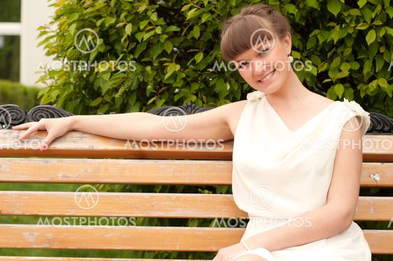 A beautiful woman is sitting on a park bench