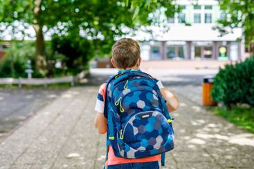 Happy little kid boy with satchel. Schoolkid on the way...