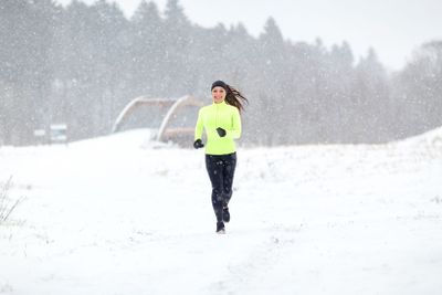 happy smiling woman running outdoors in winter