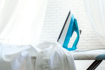 Iron on ironing board on light home interior background