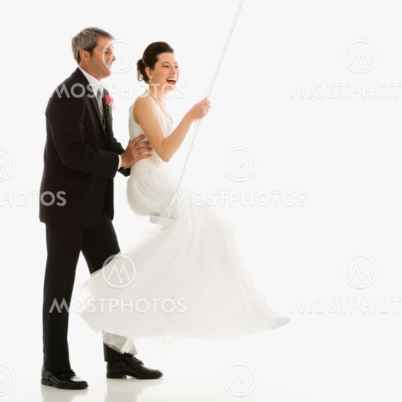 Groom pushing bride in swing.