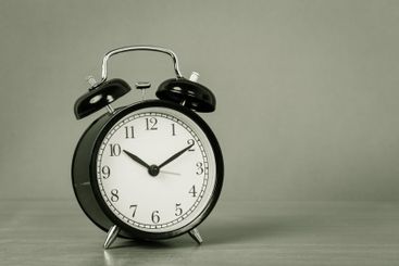 Black vintage alarm clock on wooden table