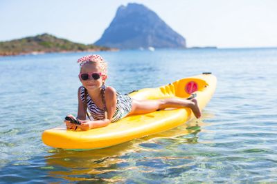Adorable little girl kayaking in blue sea during summer...