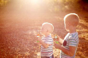 Happy, blowing bubbles and children in park for fun,...