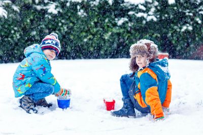 Two little kid boys playing with snow outdoors