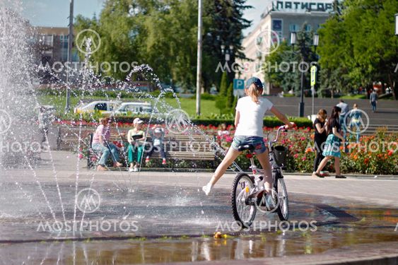 Children near a splashing fontain in the center of town...
