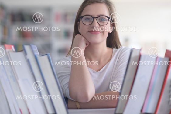 portrait of famale student selecting book to read in...