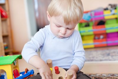 Little toddler boy playing with wooden toys