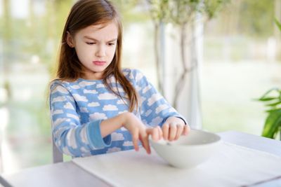 Portrait of moody girl sitting at breakfast table