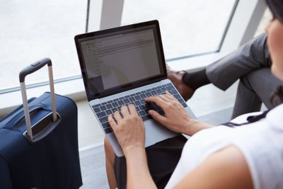 Businesswoman Using Laptop In Airport Departure Lounge