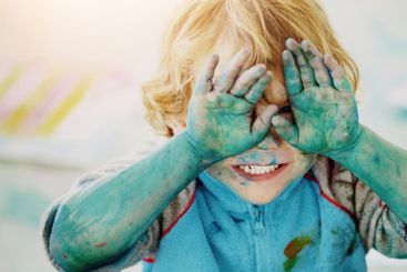 Paint, toddler and eyes covered for fun, joy and...