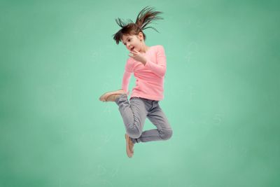 happy little girl jumping in air over school board