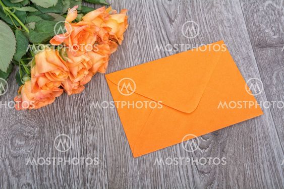 Orange envelope and roses on a wooden background