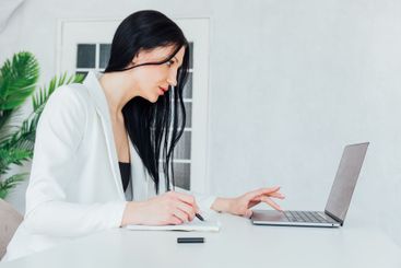 Brunette Woman In White Business Suit With Laptop Online...