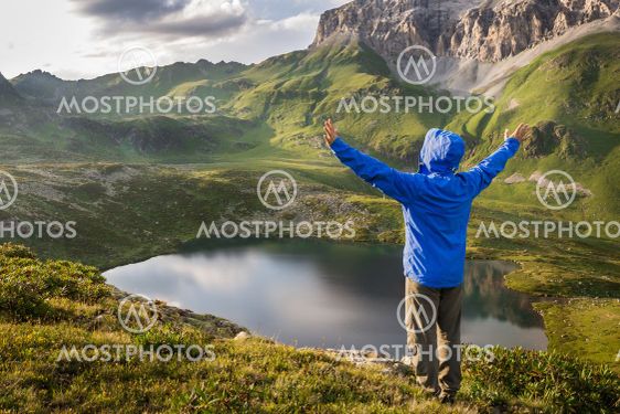 Hiker standing with raised hands near beautiful mountain...